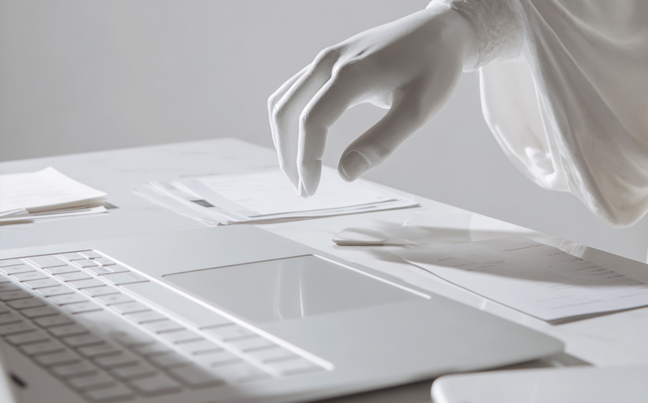 Main de statue au-dessus d’un clavier d’ordinateur, évoquant la réflexion d’une stratégie de communication.
